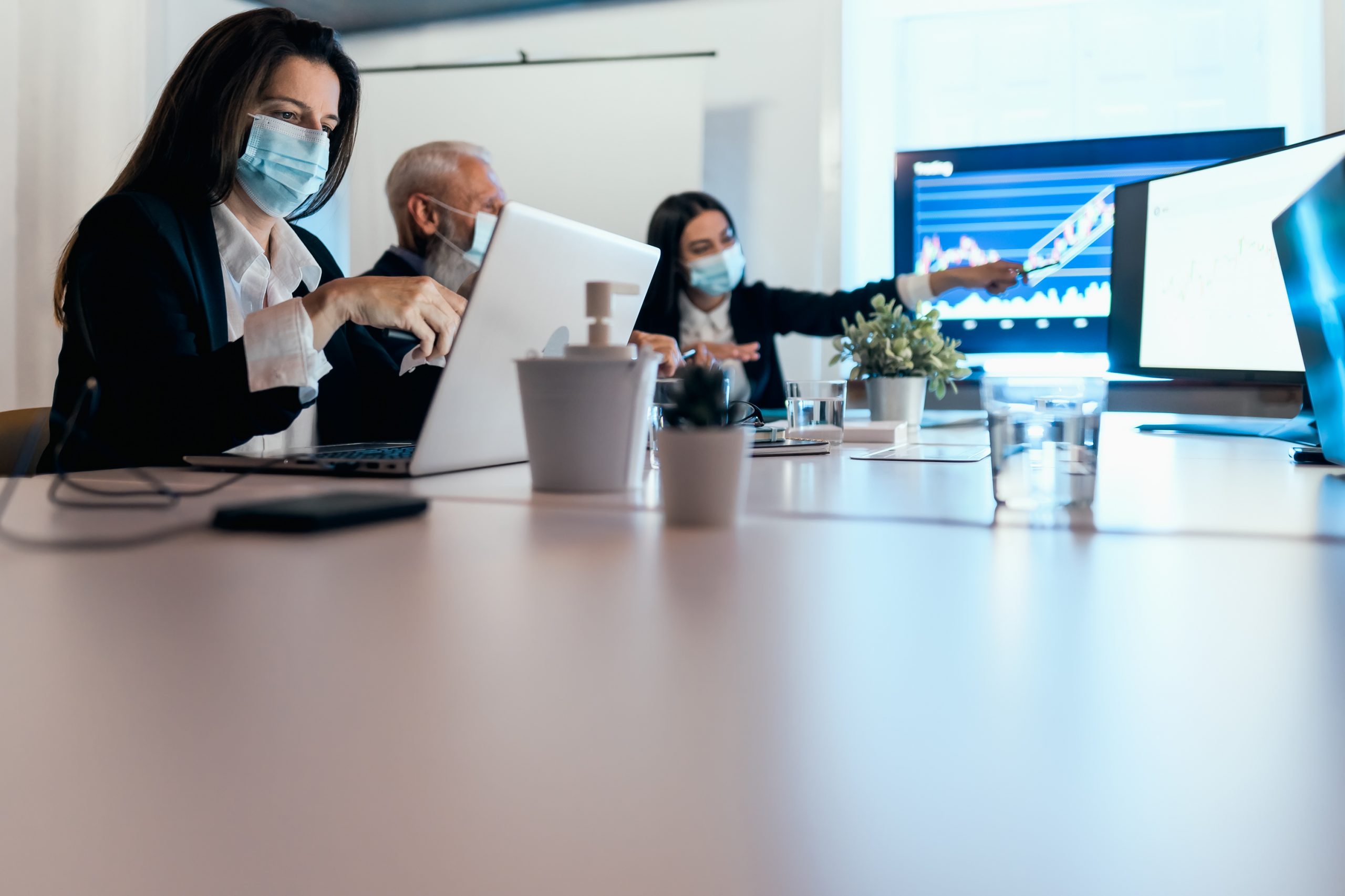 Business stock traders in meeting room working on crypto currency markets with blockchain technology wearing face mask during corona virus outbreak - Decentralized finance and stock exchange concept
