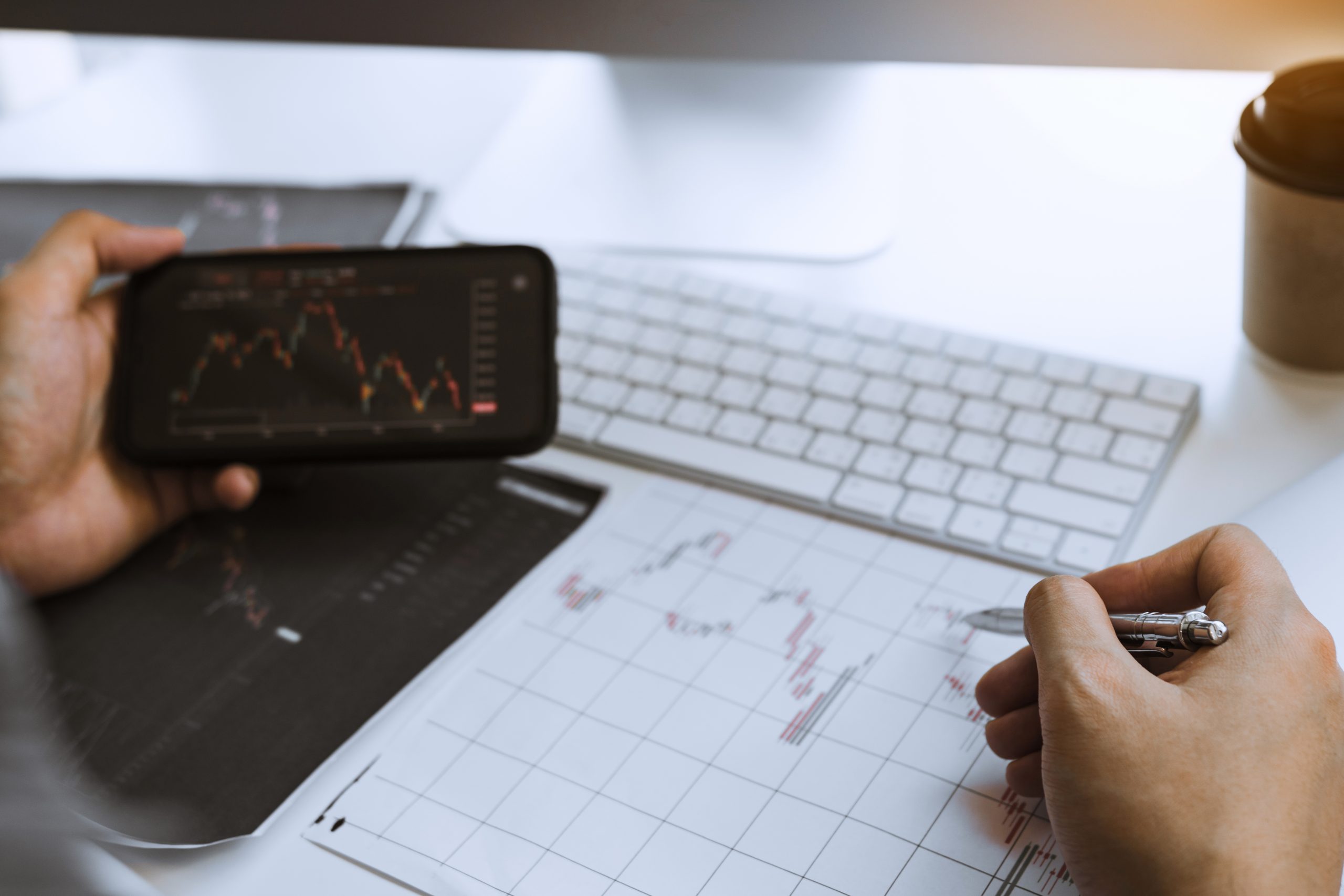 Investors use smartphones view investment graphs and record statistics on stock performance results for use in investment analysis.