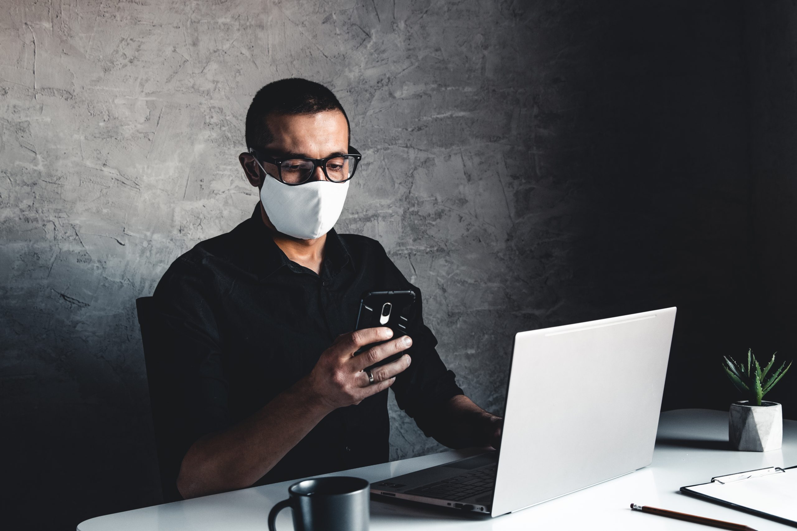 A masked man works at a computer. Pandemic, coronavirus, epidemic