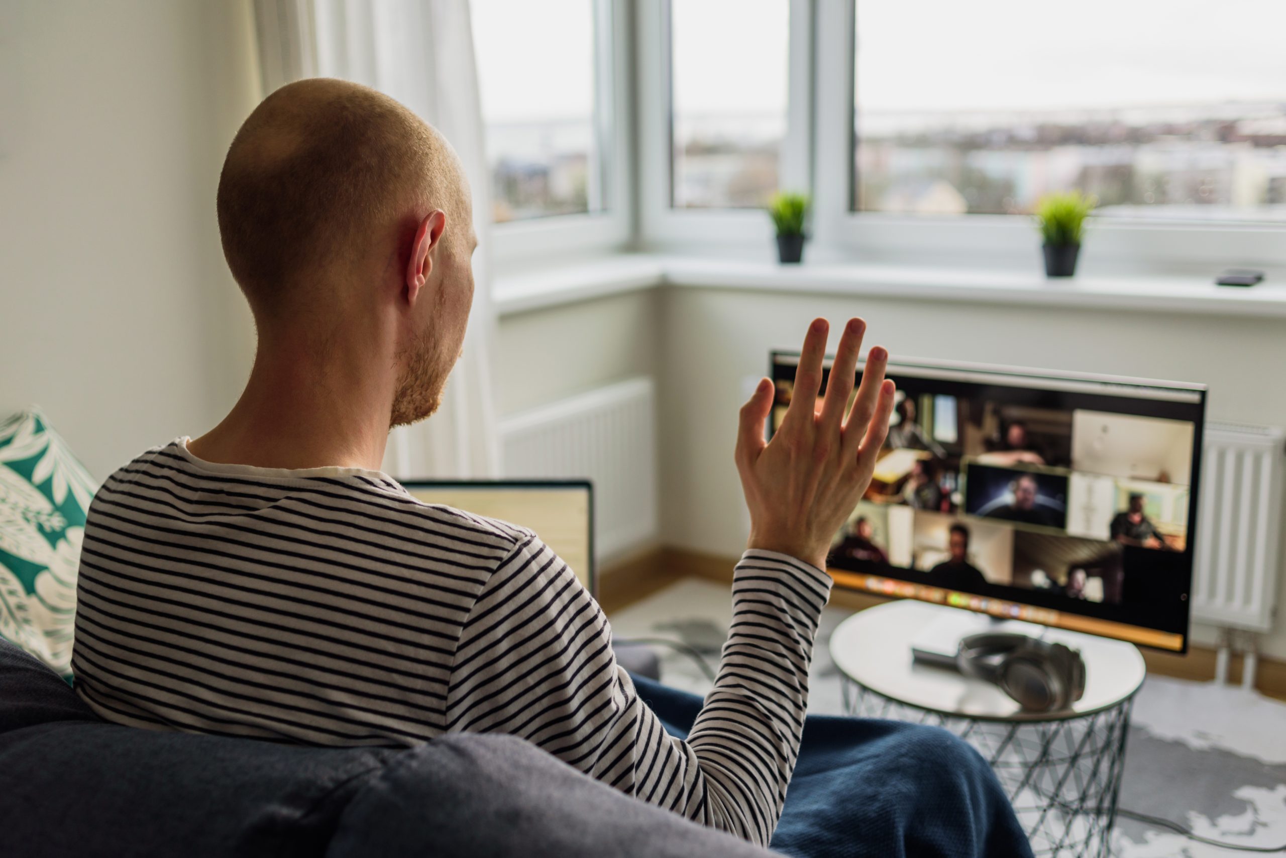 Man working from home. Having a video call meeting with his team on big monitor