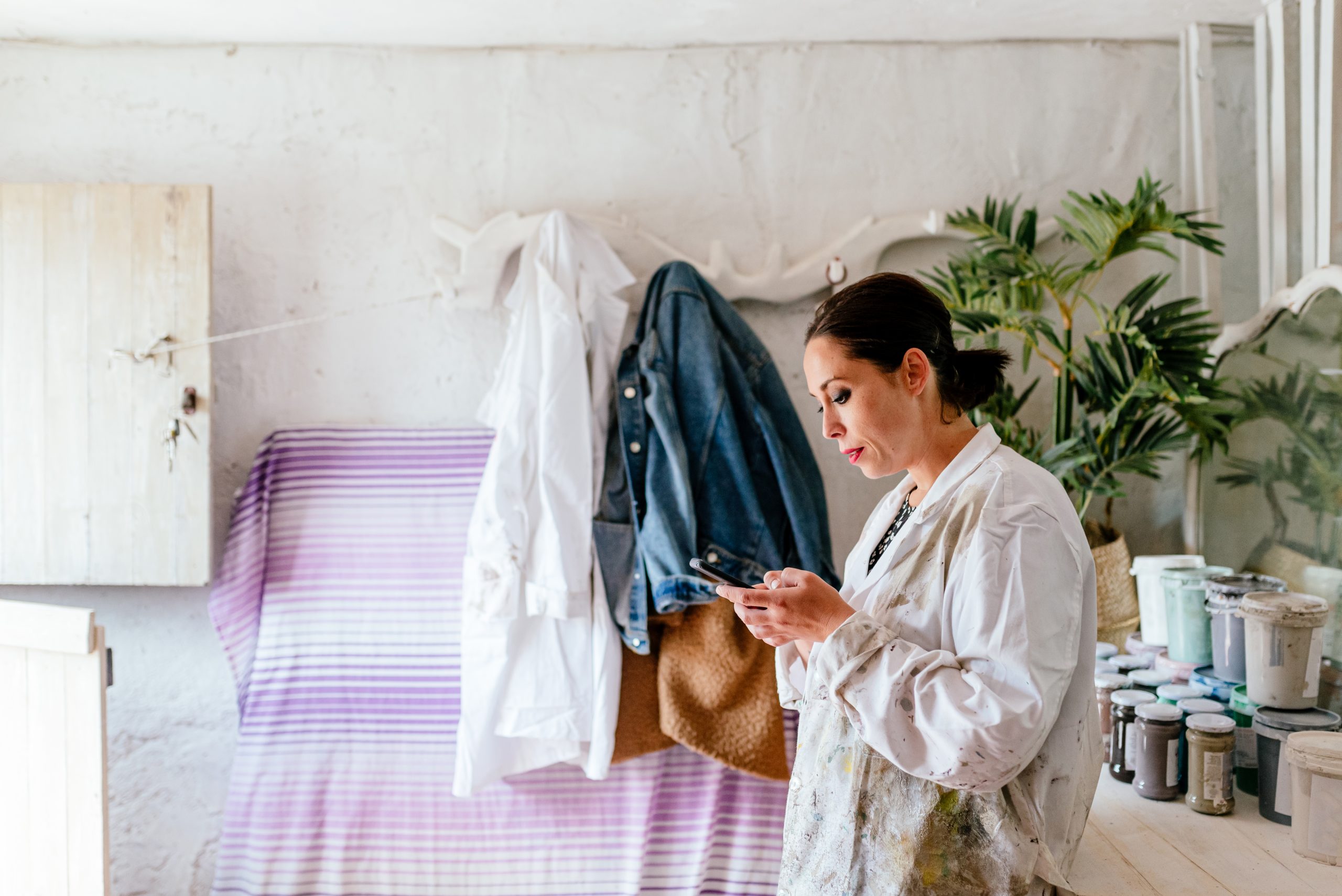 enterprising woman using her smartphone in her carpentry and restoration workshop. businesswoman.